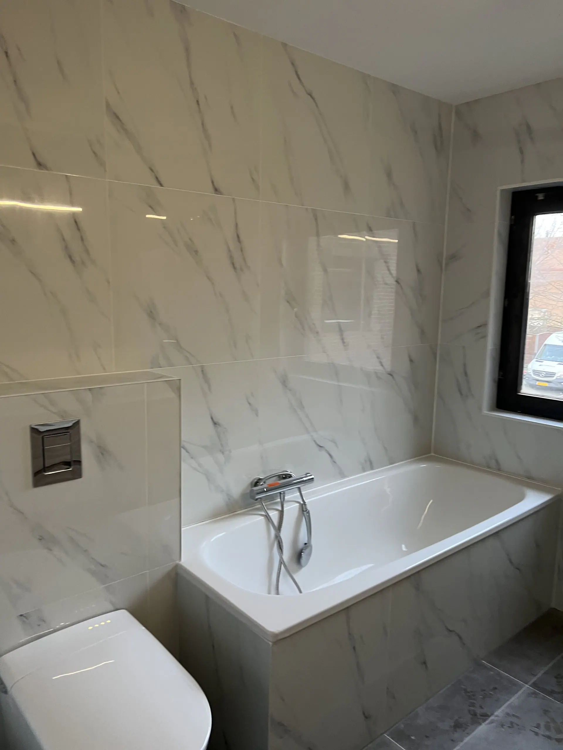 Ligbad en hangend toilet tegen marmerlook tegels