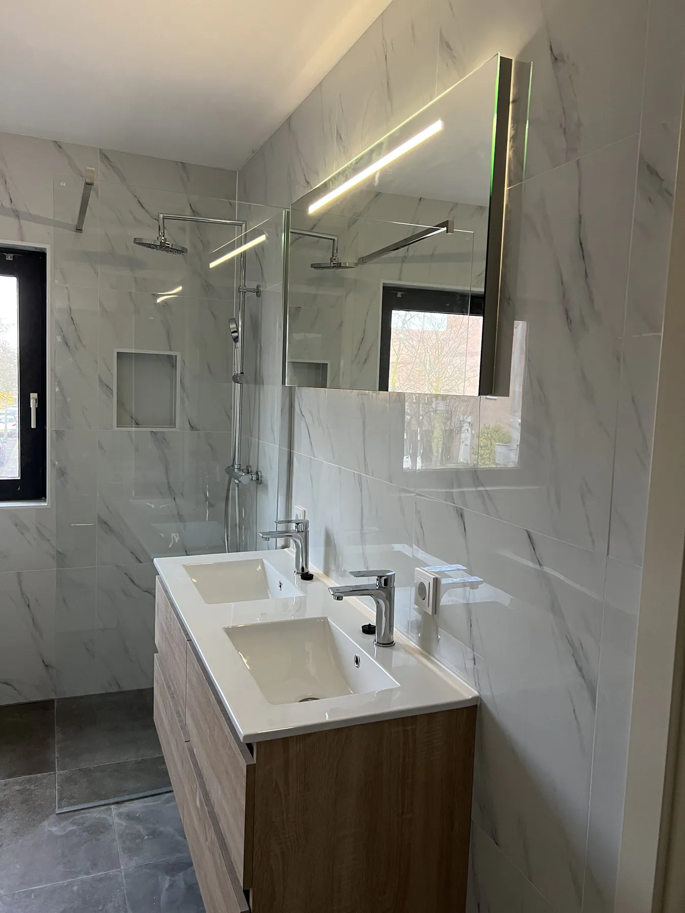 Badmeubel en douche met verlichte spiegel