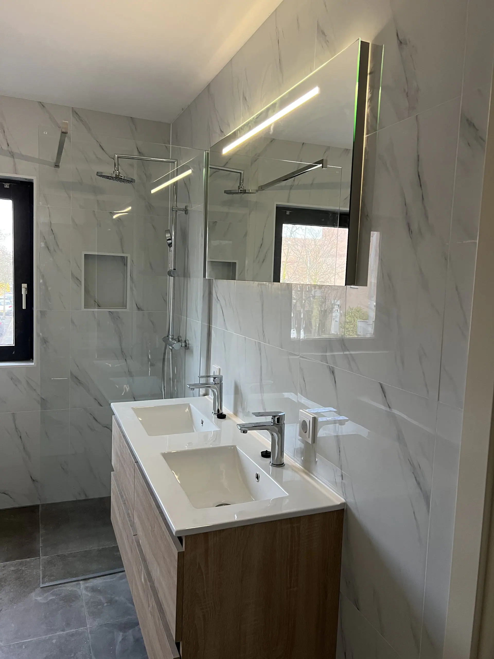 Badmeubel en douche met verlichte spiegel