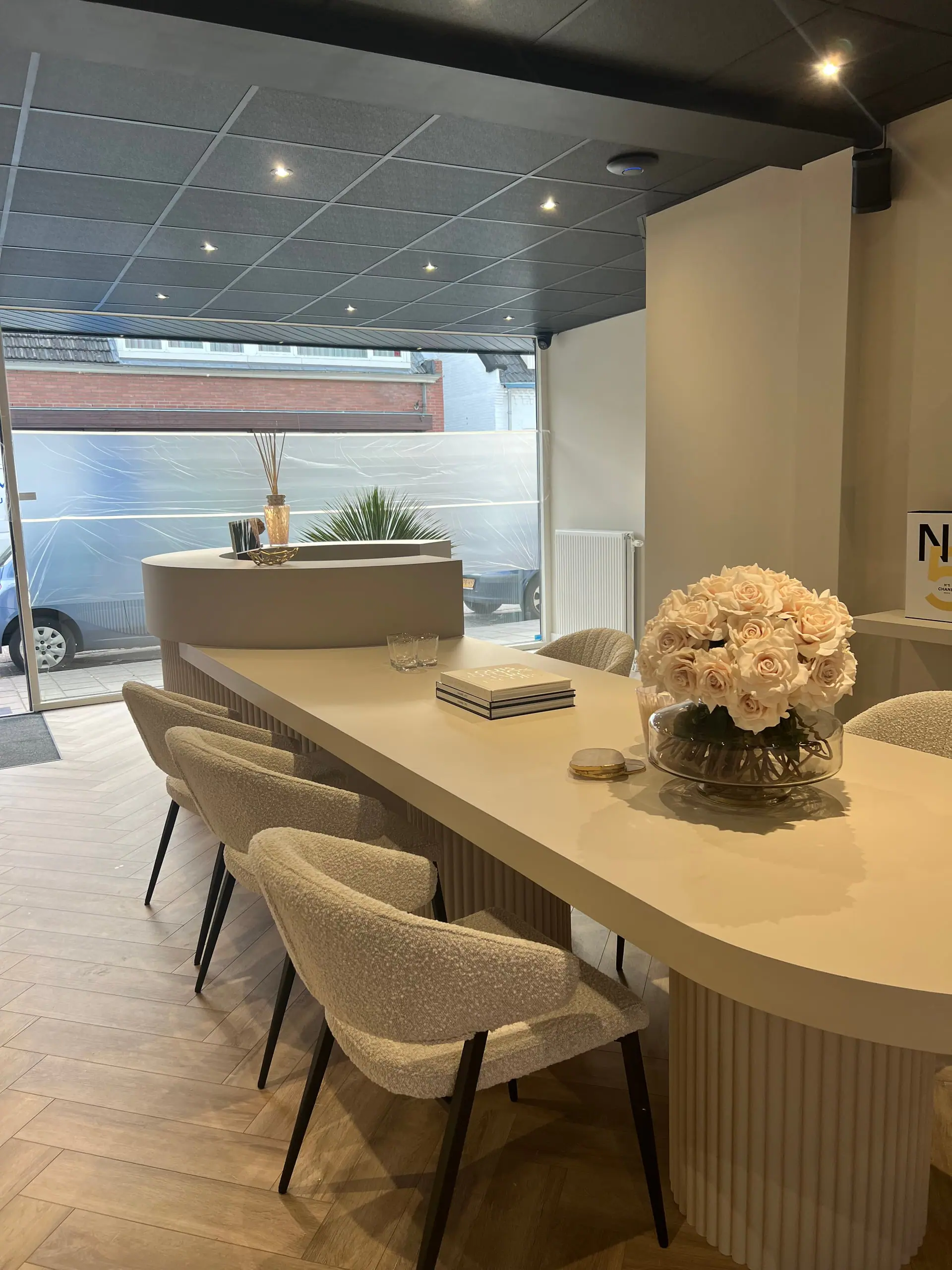 De wachtruimte met bouclé stoelen en lattenwand