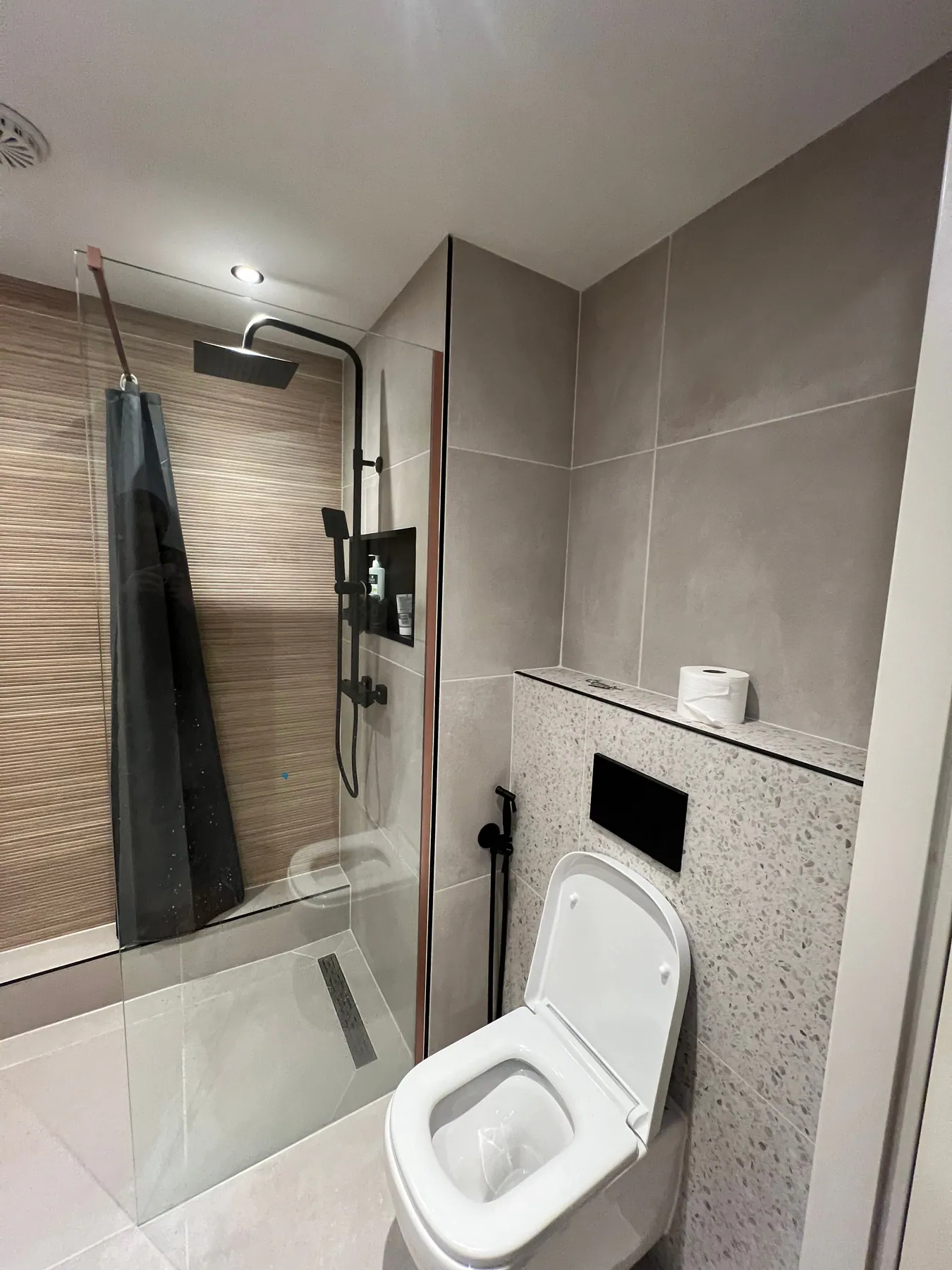 De tweede badkamer: toilet met terrazzo wand en spiegel